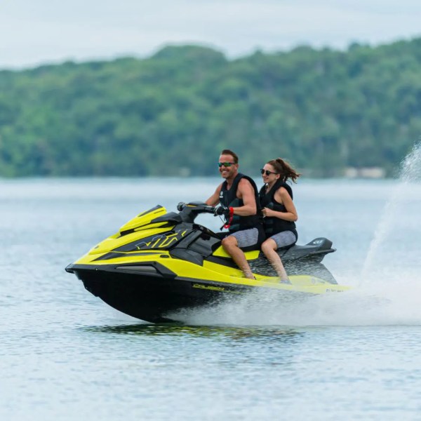 Two people riding a yellow jet ski on a lake.