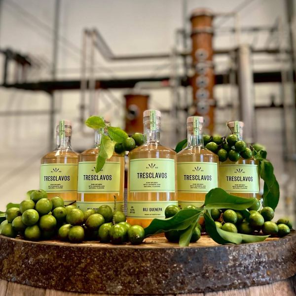 Bottles of Tresclavos liquor with green fruits on a barrel.