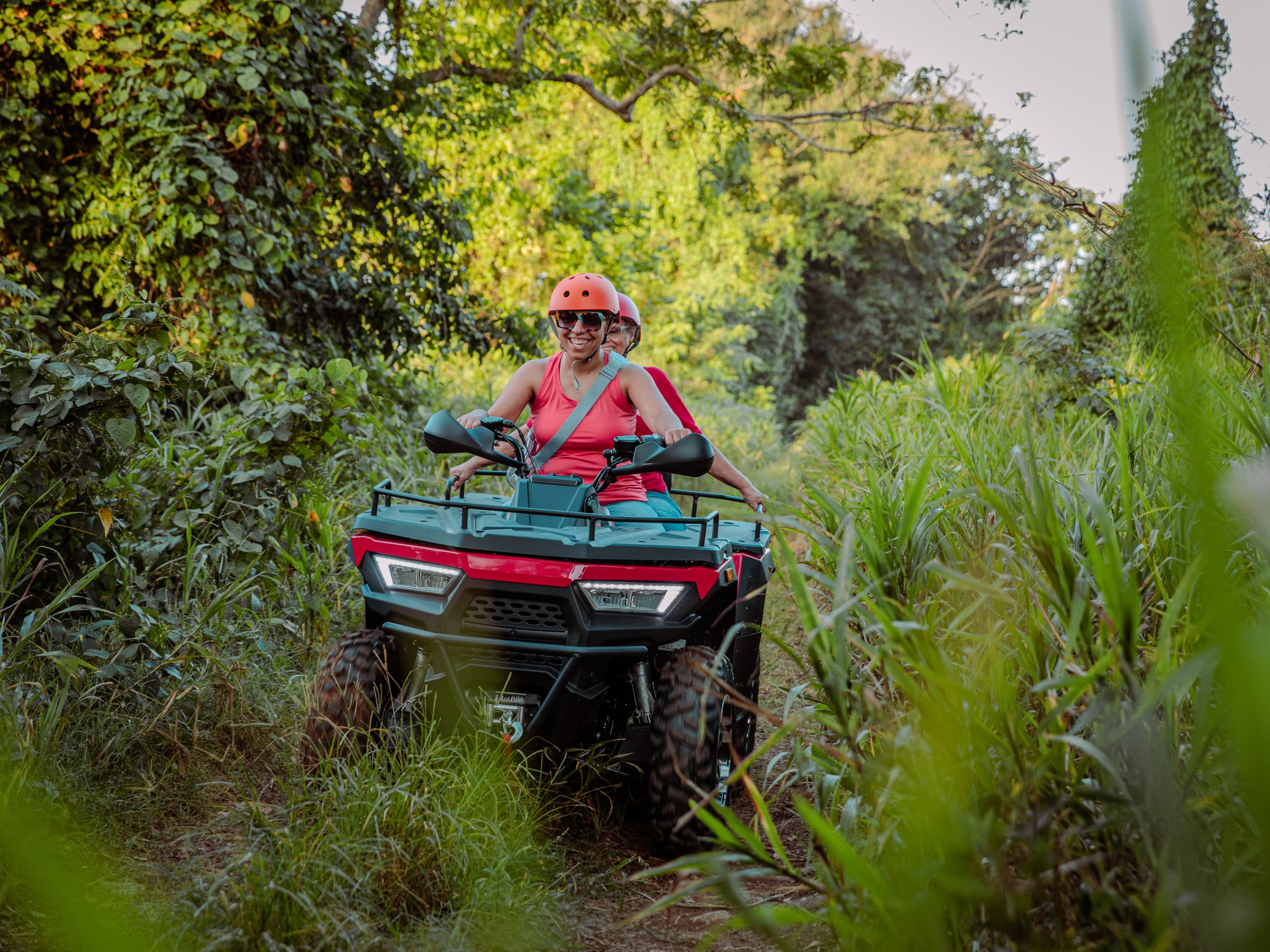 Person on an ATV riding through a lush, green forest trail.