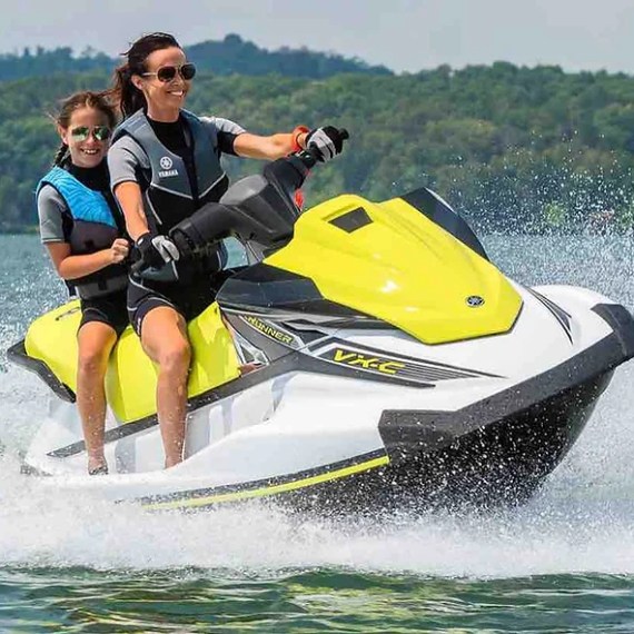 Two people riding a yellow jet ski on a lake.