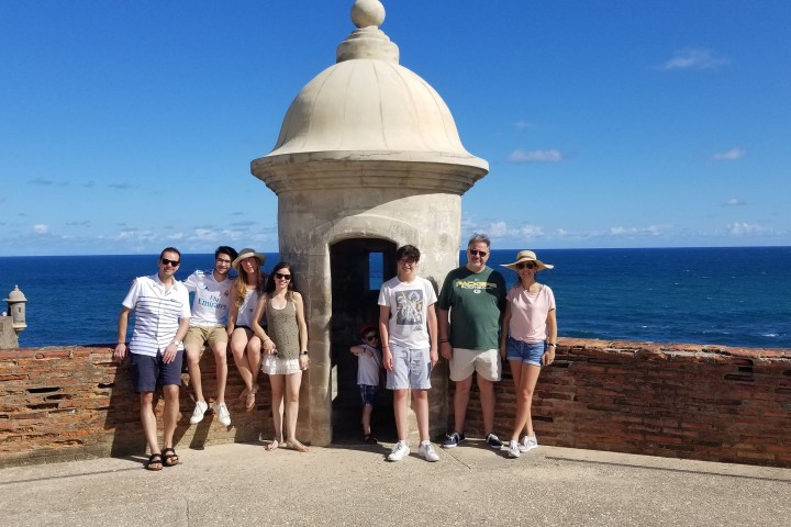 Group of people posing near a stone turret with ocean in the background.