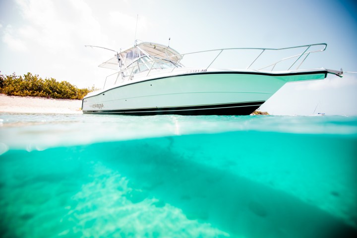 Boat on clear turquoise water with beach in background.