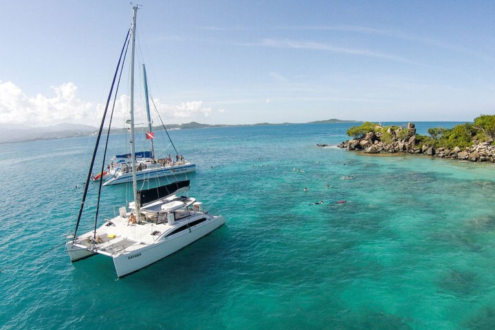 Catamaran near a tropical island with clear blue water.