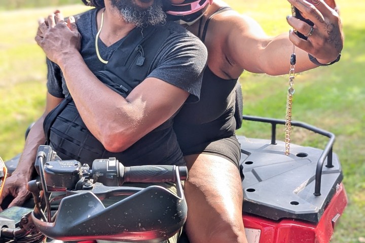 Two people on an ATV taking a selfie outdoors.