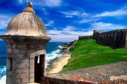 Old fort tower by the sea with blue sky and green grass.