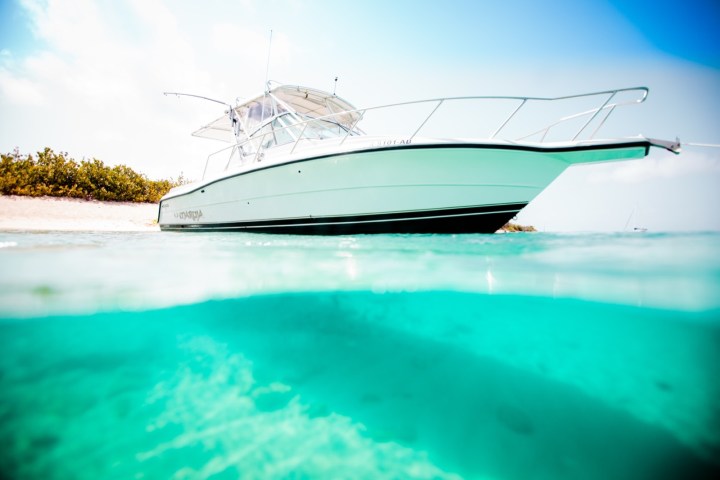 Boat near a sandy beach with turquoise water and clear sky.