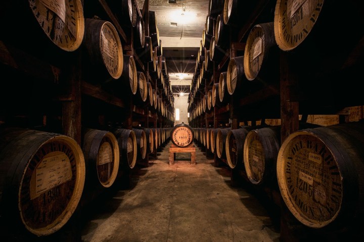 A dimly lit warehouse with rows of wooden barrels.