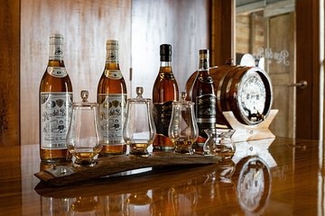 Whiskey bottles and glasses on a wooden table with a small barrel.