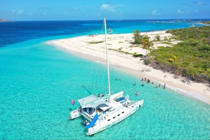 Catamaran anchored near a tropical beach with clear turquoise water.