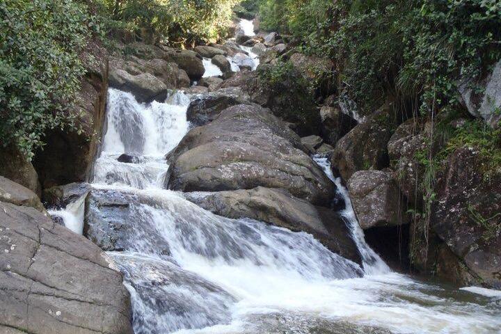 Waterfall cascading over rocks in a lush, forested area.